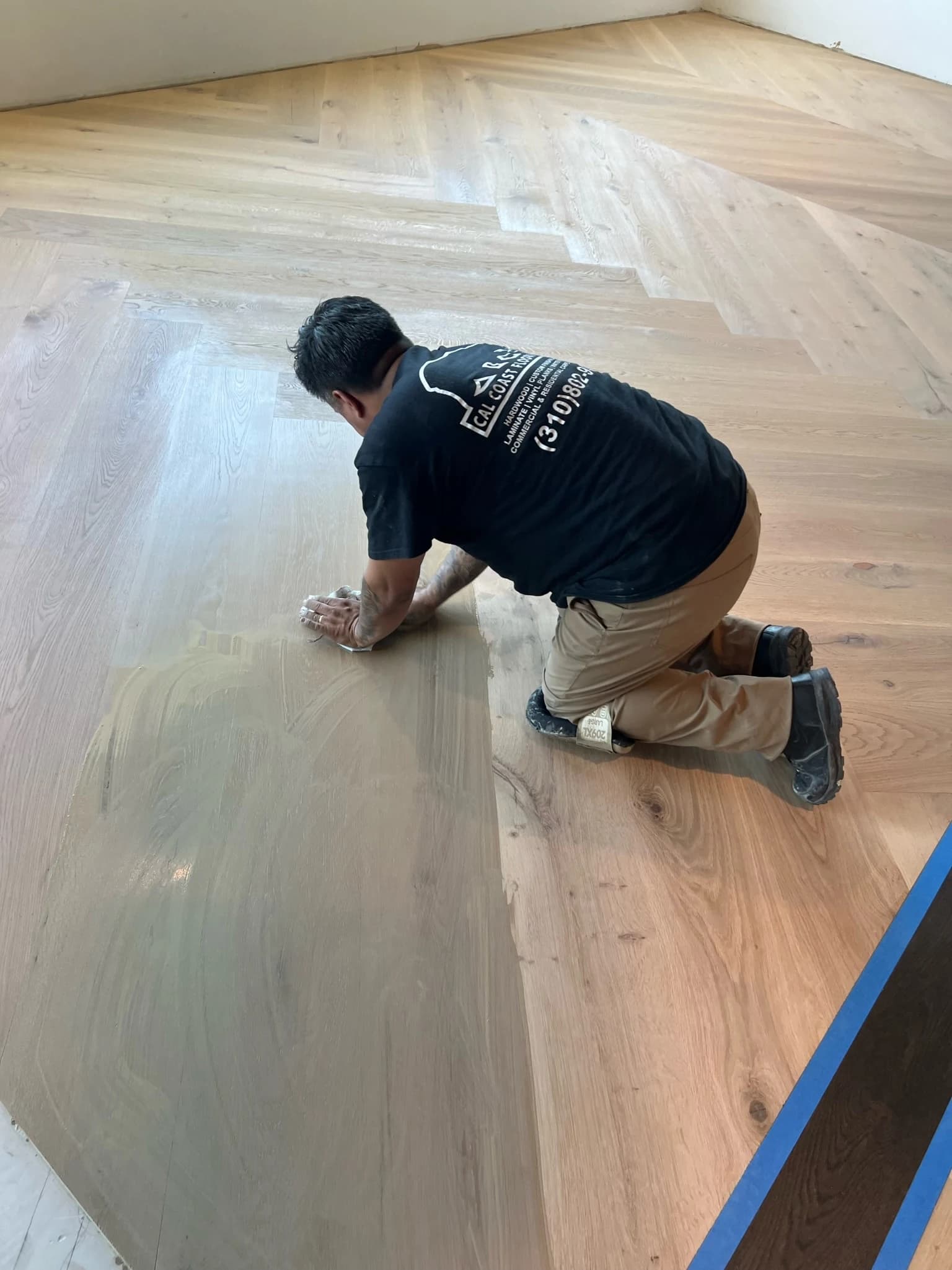 Cal Coast Flooring installer hand-applying a custom stain to an oak herringbone floor on Pacific Coast Highway, Lomita